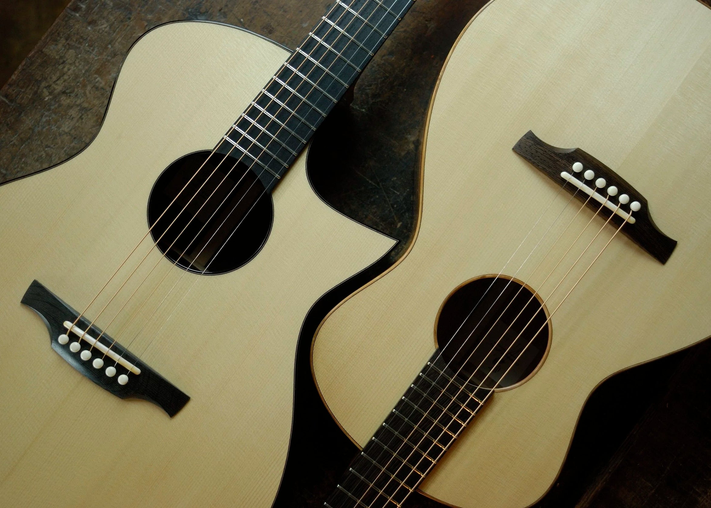 Two Swannell acoustic guitars with a dark background