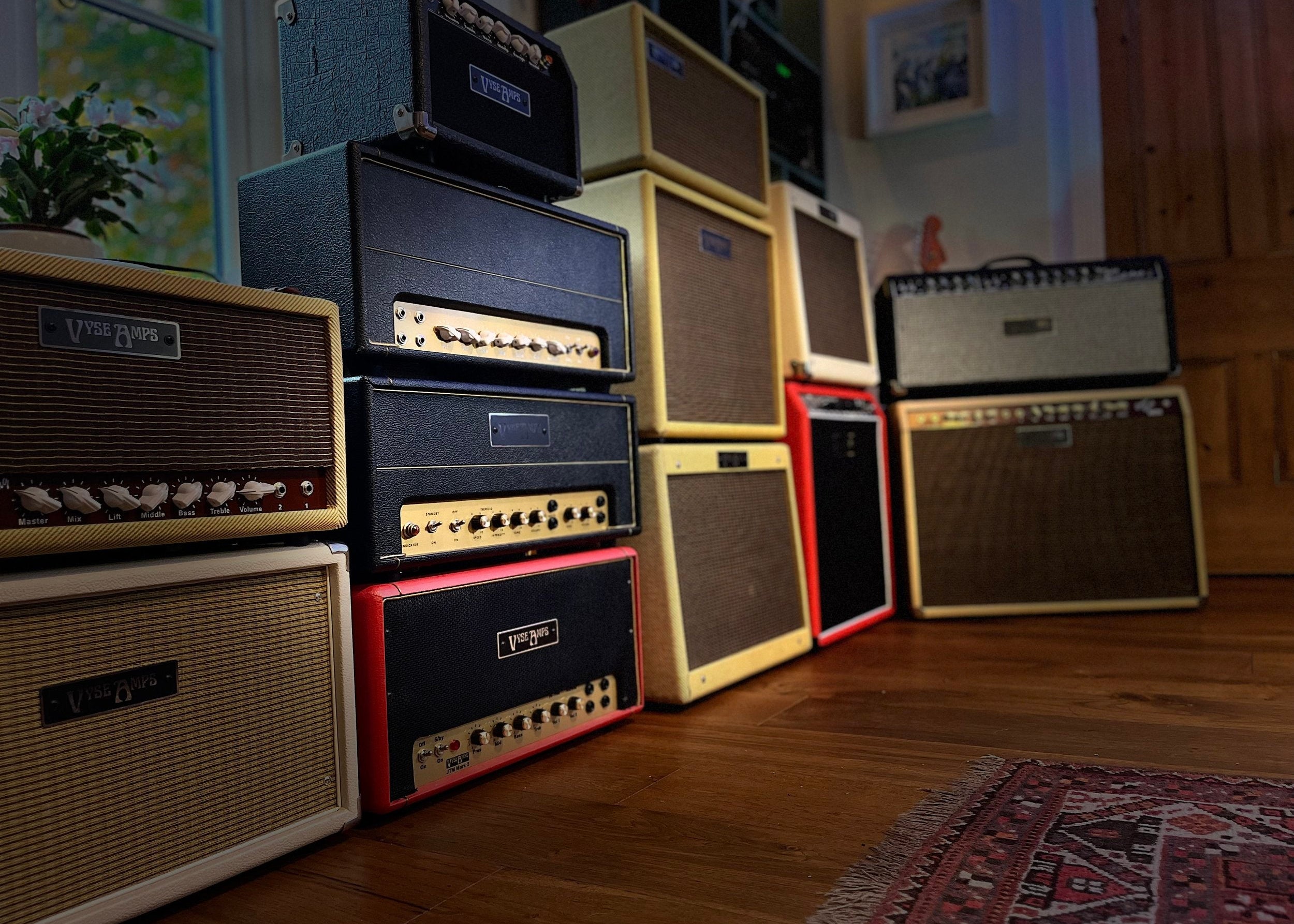 Collection of Vyse vintage guitar amplifiers stacked on a wooden floor.