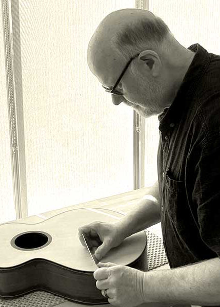 Mike Hobbs working on a guitar in a workshop setting